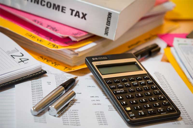 Pile of tax materials with an income tax book, papers and a calculator